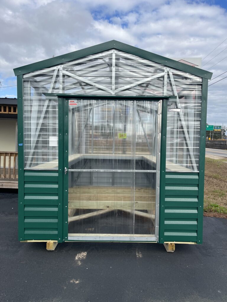 Greenhouse with green trim, a wide doorway, and a gabled roof